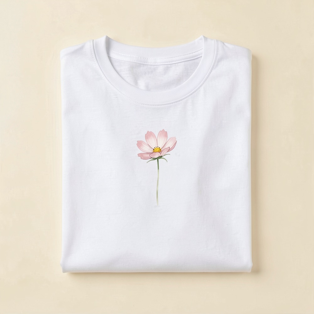 Folded natural-white t-shirt with a watercolour pink cosmos flower printed on the chest
